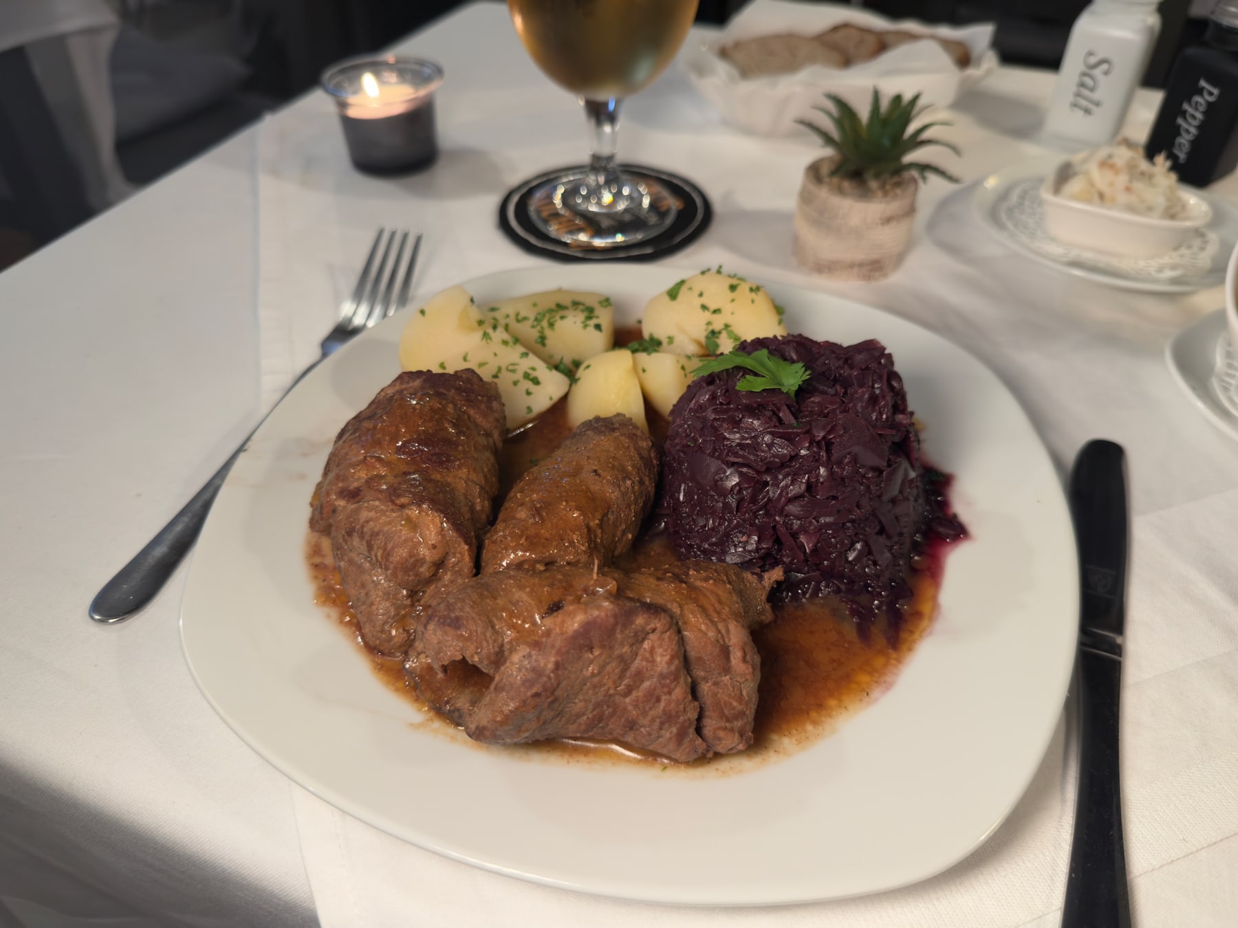 Rinderrouladen mit Rotkraut und Salzkartoffeln auf weißem Teller